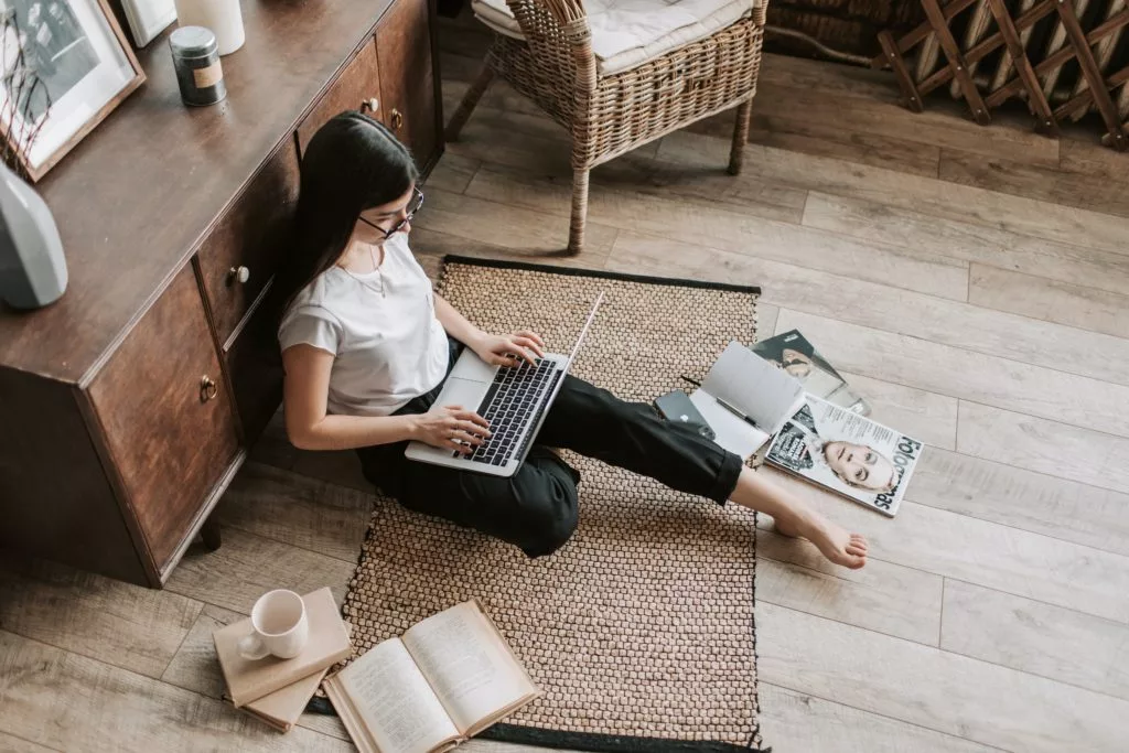 woman booking a trip online on the floor of her living room